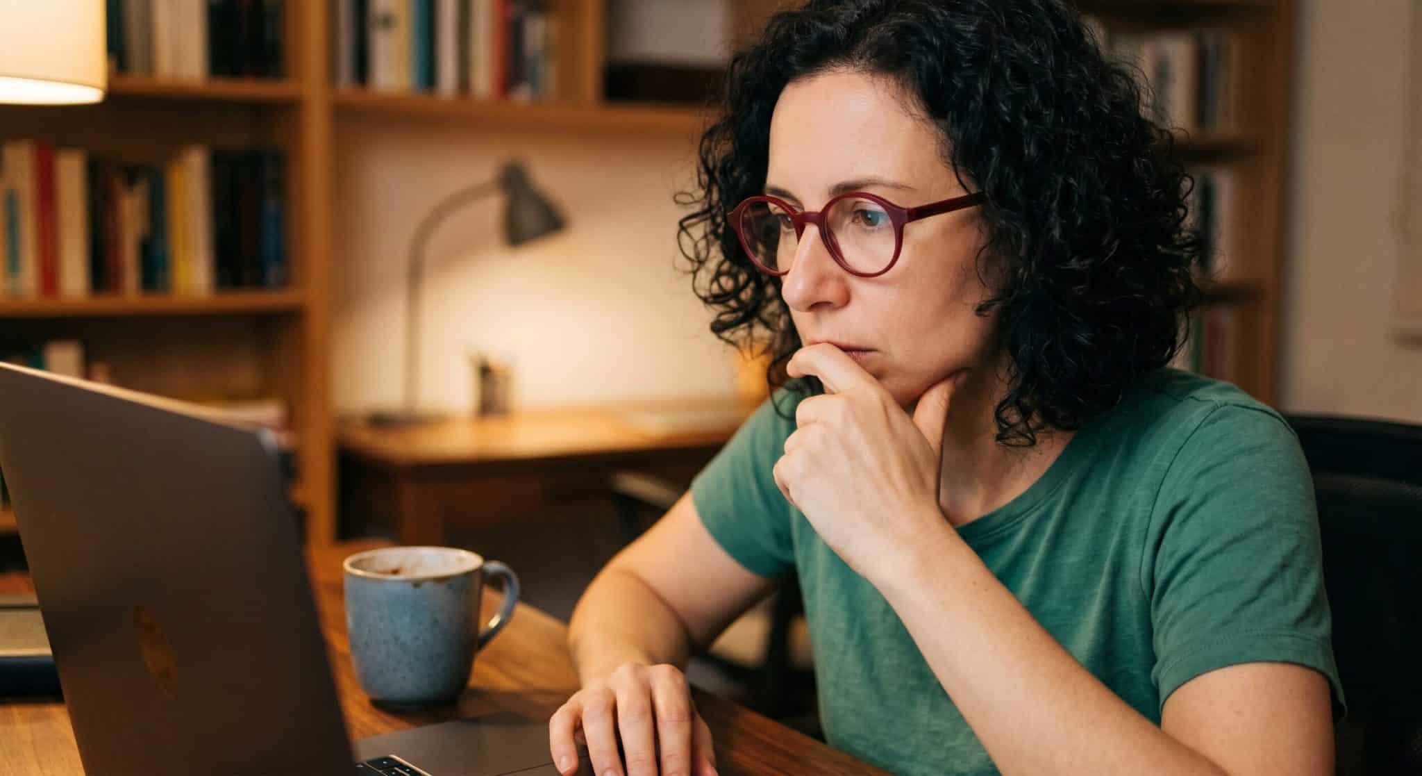 woman curly hair and glasses looking at computer 1